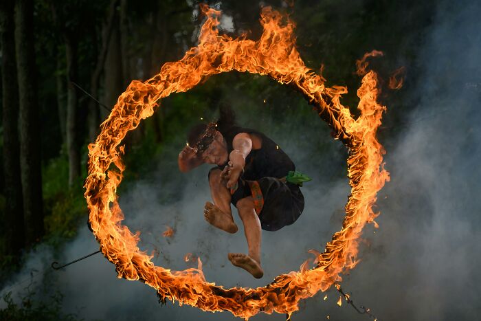 Person jumping through a flaming hoop in a dark forest setting, illustrating mind-bending scenarios challenging your morals.