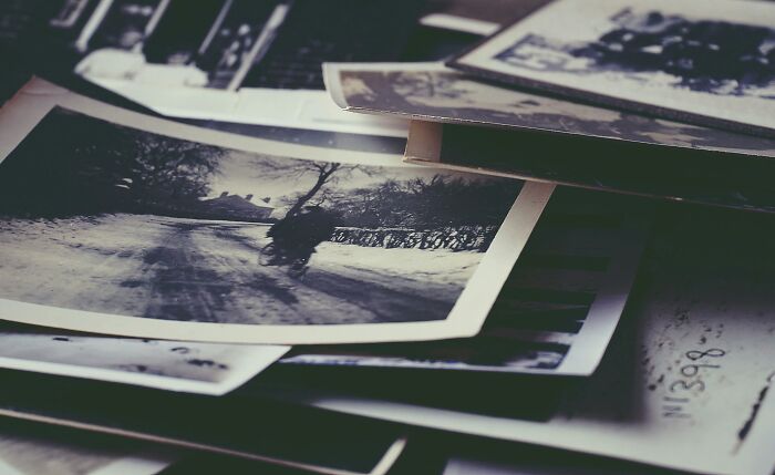 Vintage black and white photographs scattered on a table, evoking mind-bending scenarios that challenge your morals.
