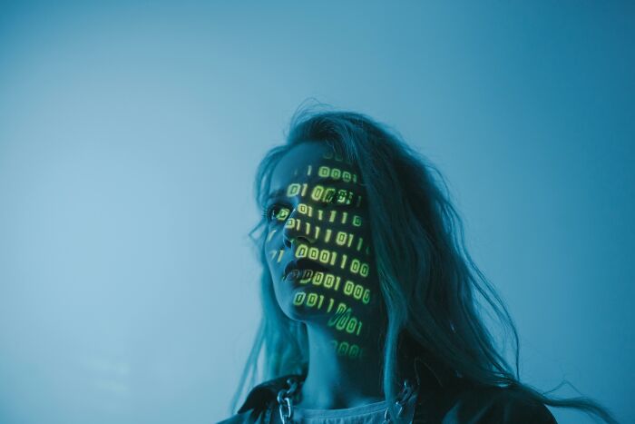 Young woman with binary code projected on her face, representing mind-bending scenarios that challenge your morals.