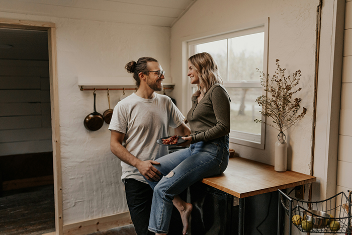 Young couple smiling in cozy kitchen, highlighting relationship trust and issues around rent and deception.