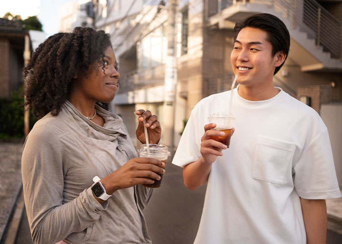 Two people enjoying drinks and smiling outdoors, highlighting common myths about men that are simply not true.