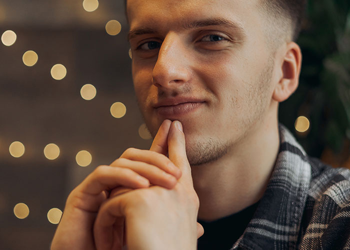 Young man with a thoughtful expression, sharing insights about common myths about men in a cozy setting with soft lights.