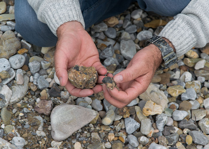 Person wearing a gray sweater examining rocks with hands over a gravel surface illustrating men share myths about them concept.