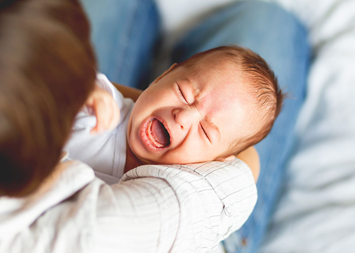 Baby crying in a man's arms, illustrating emotional moments related to myths about men that are simply not true.