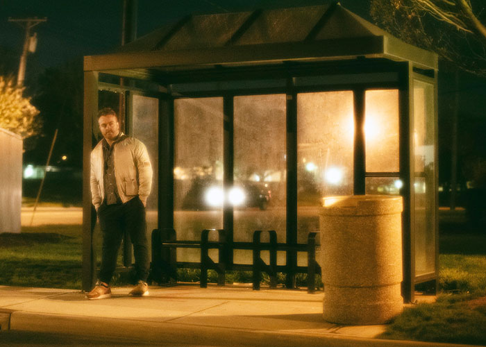 Man standing alone at a bus shelter at night, illustrating common myths about men that are simply not true.