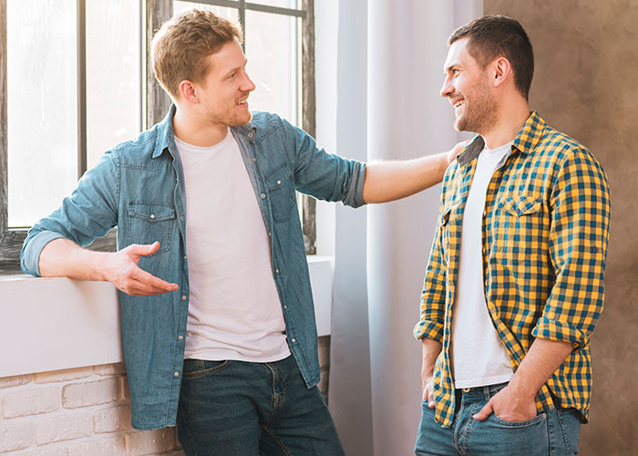 Two men casually talking indoors, illustrating common myths about men through friendly conversation.