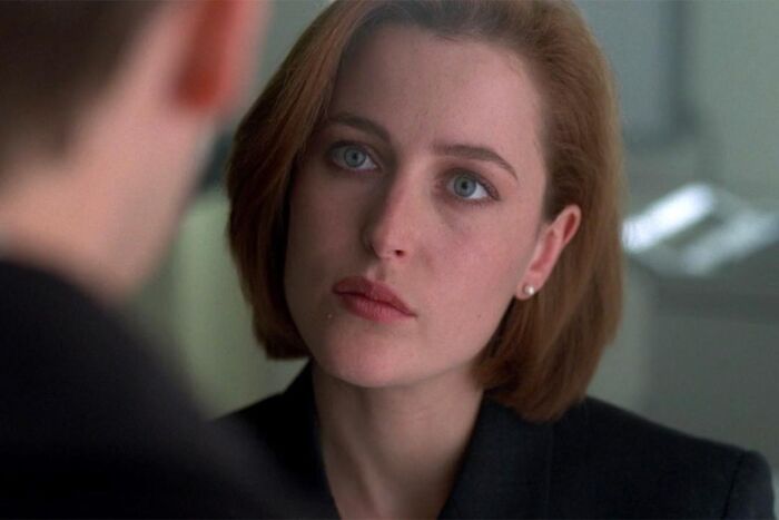 Close-up of a woman with short hair and blue eyes showing a serious expression in a scene highlighting unrealistic women movie tropes.