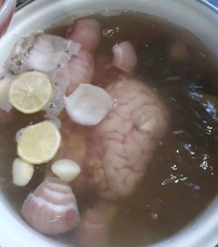 Bowl of shrimp jello with lemon slices and gelatinous seafood pieces, an unusual dish served to guests.