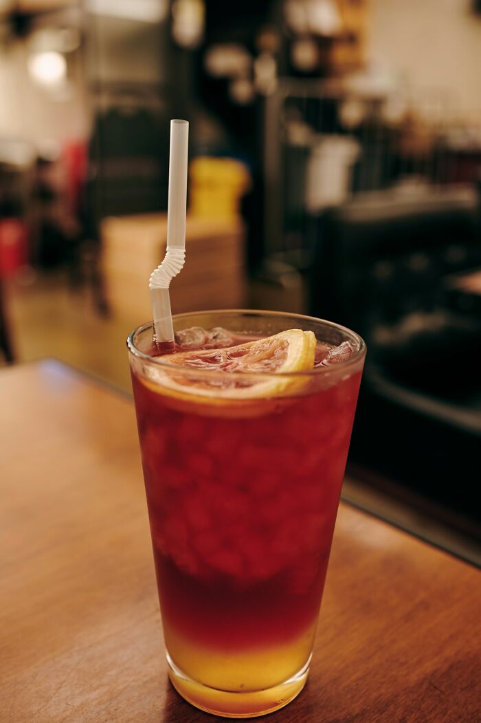Glass of iced tea with lemon slice on a wooden table in a cozy cafe, capturing embarrassing moments humorously.
