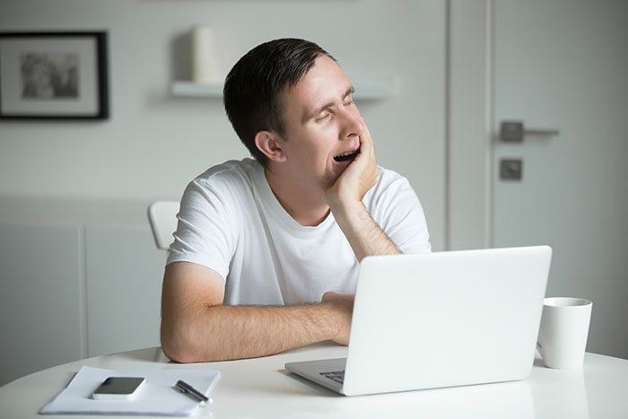 Tired husband yawning at a laptop, feeling burnt-out and struggling with feeding the baby once a night request. Tired husband yawning at a laptop, feeling burnt-out and struggling with feeding the baby once a night request.