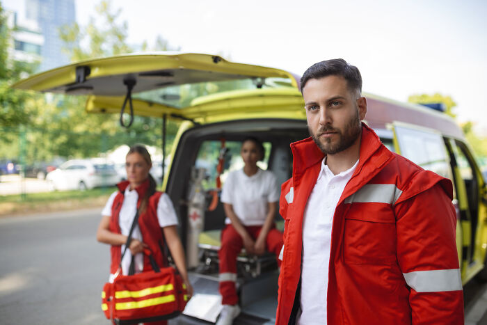 Paramedics in red uniforms standing near an ambulance responding to one of the strangest calls 911 operators received.