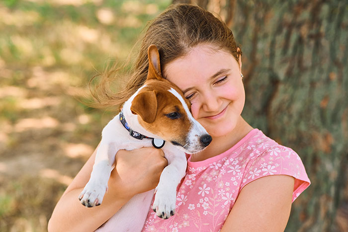 Woman holding and hugging her dog outdoors, illustrating woman adopts dog and challenges with previous owners.