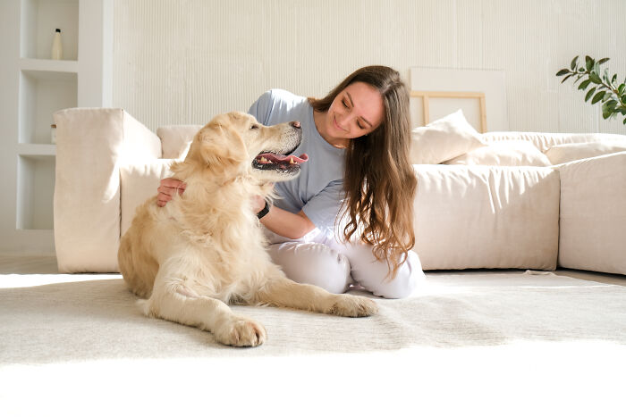Woman sitting on the floor with her intelligent dog, showing affectionate moments that surprise pet owners indoors.