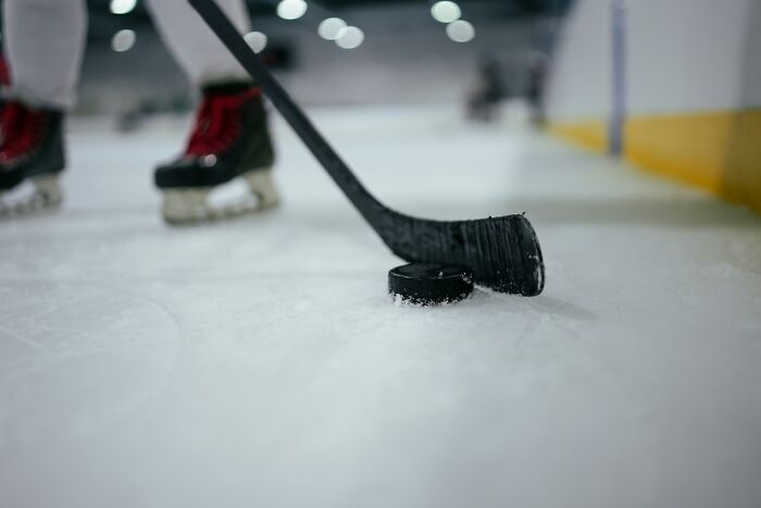 Hockey player on ice rink about to hit puck, illustrating persistence linked to long grudges people reveal.