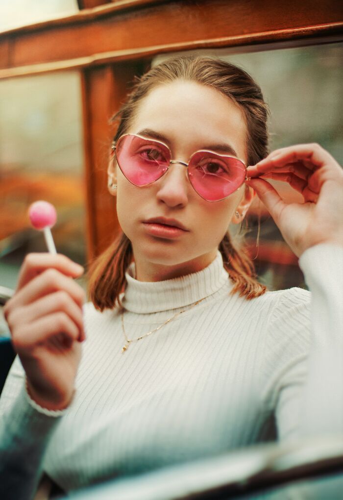 Young woman wearing heart-shaped sunglasses and holding a lollipop, reflecting on marriage red flags and spouse changes.