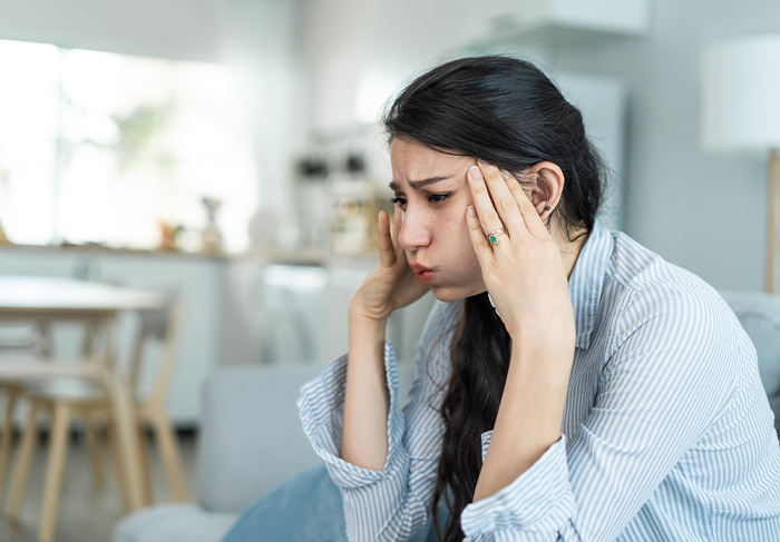 Stressed spiritual bride holding her head in hands, facing chaos and shock two weeks before the wedding.
