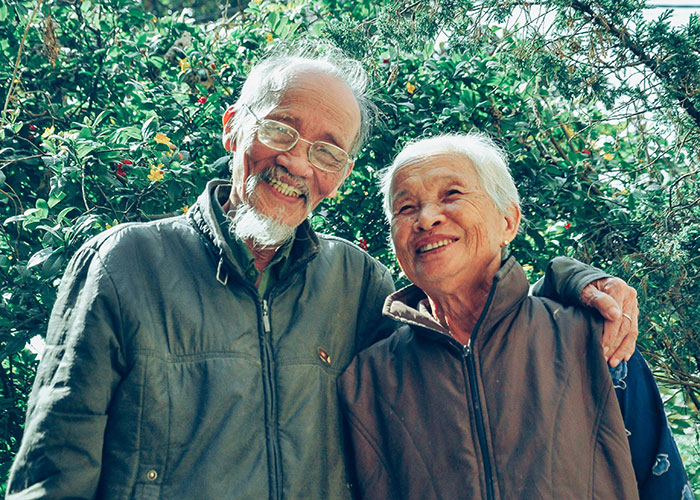 Elderly couple smiling outdoors, highlighting family events scheduled on woman&rsquo;s work days and work priorities.