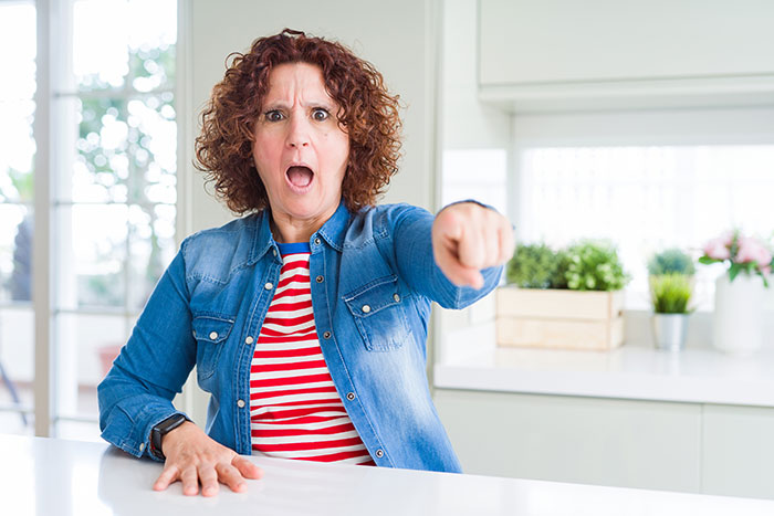Angry mom pointing and upset in kitchen, reflecting tension about celebrating kids birthdays during holidays. Angry mom pointing and upset in kitchen, reflecting tension about celebrating kids birthdays during holidays.