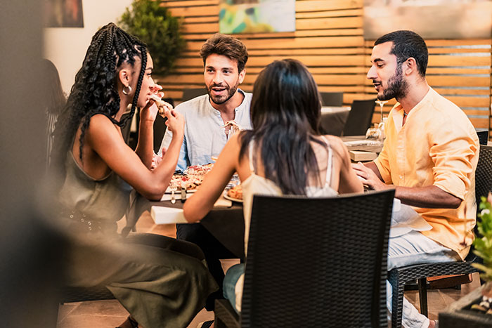 Group of friends dining together outdoors, one man taking advantage during the meal, causing tension at the table. Group of friends dining together outdoors, one man taking advantage during the meal, causing tension at the table.