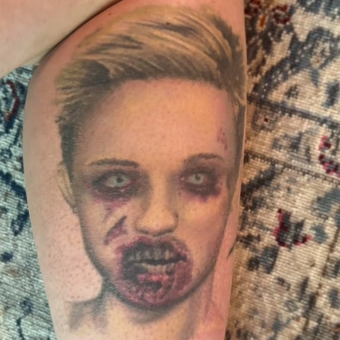 Tattoo artist's viral Miley tattoo regret showing a bruised and bruised face portrait on a forearm against a patterned background.