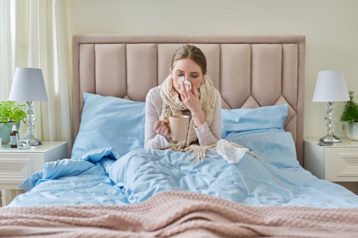 Sick woman in bed holding a cup, symbolizing emotional strain as man prioritizes work over family life. Sick woman in bed holding a cup, symbolizing emotional strain as man prioritizes work over family life.