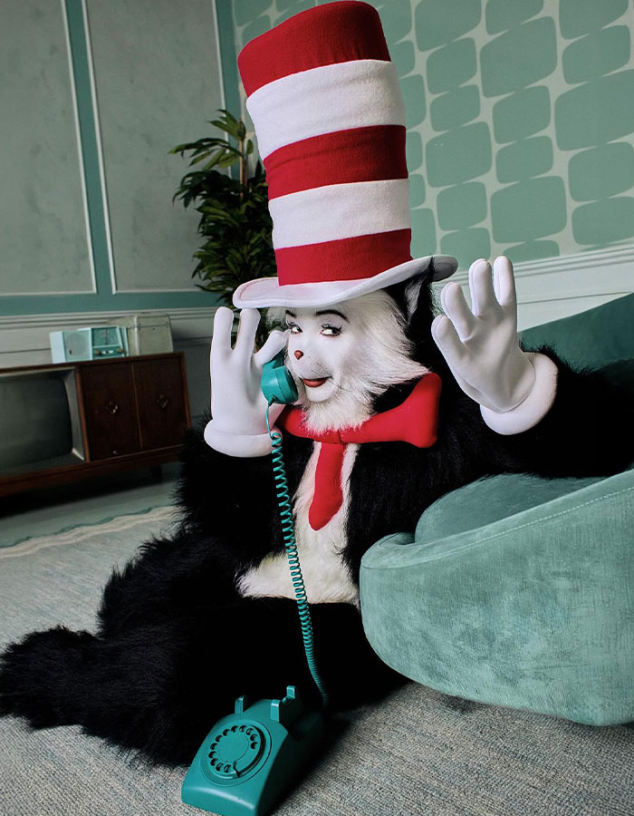 Celebrity dressed as the Cat in the Hat in a detailed costume, posing with a retro phone for Halloween costume inspiration.