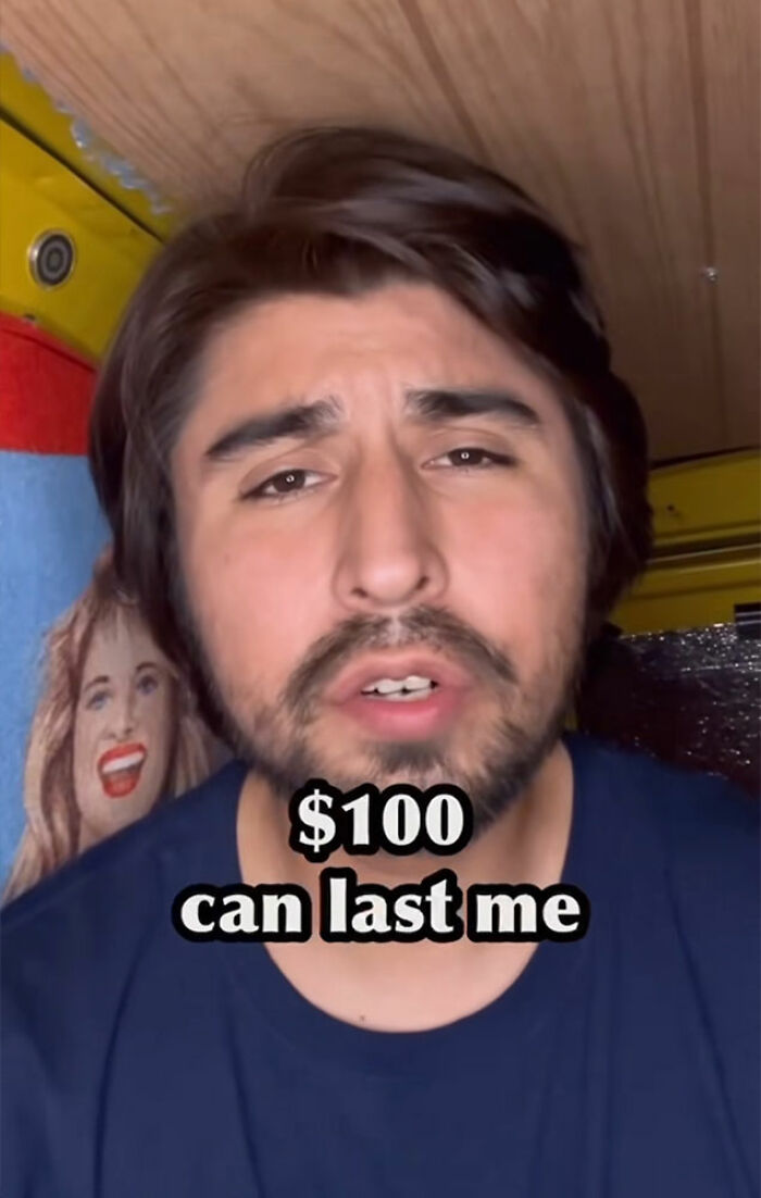 Comedian with beard explaining surviving 27 days in NYC on 100 dollars in a casual indoor setting.