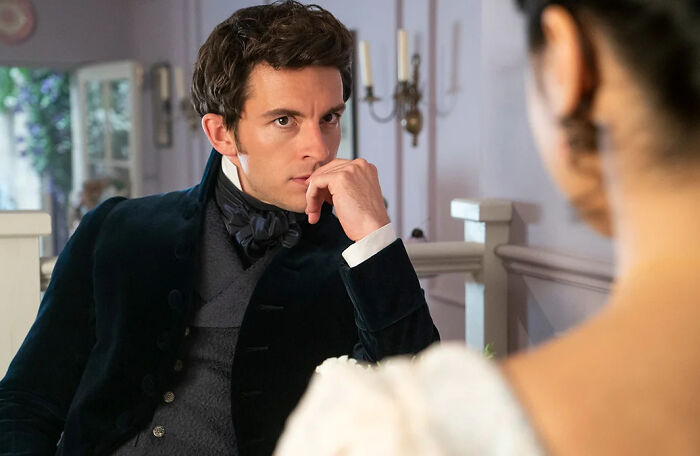 Jonathan Bailey in period costume, looking thoughtful, representing People's first openly gay Sexiest Man Alive.
