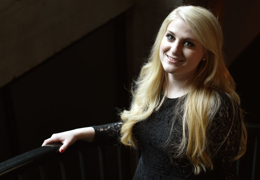 Blonde woman with long hair smiling softly wearing a black lace dress, illustrating Meghan Trainor before and after photos.
