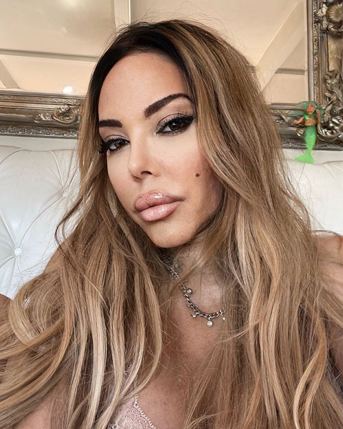 Woman with long hair and makeup posing indoors, related to fake plastic surgeon and botched silicone injections case.