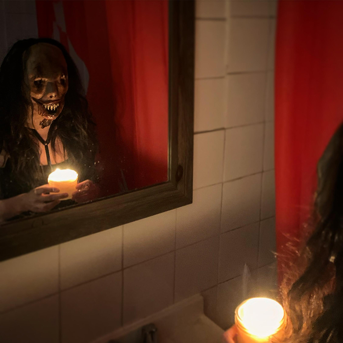 Person wearing scary mask holding a candle in front of a mirror, creating a creepy atmosphere for scary games with friends IRL.