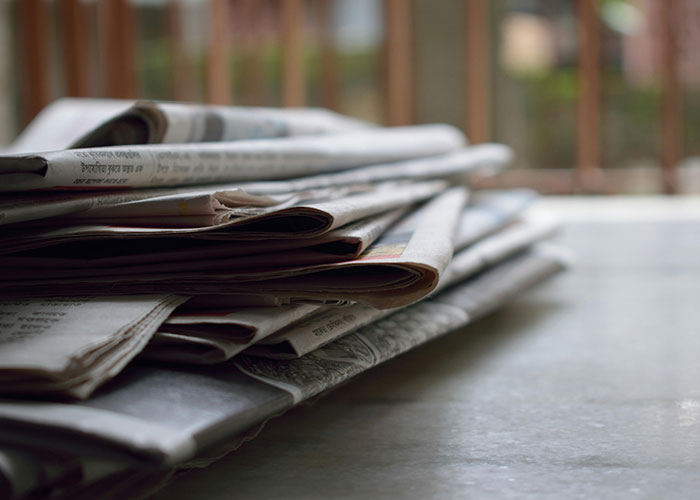 Stack of newspapers on a table representing creative cleaning hacks inspired by laziness for easy home maintenance ideas.