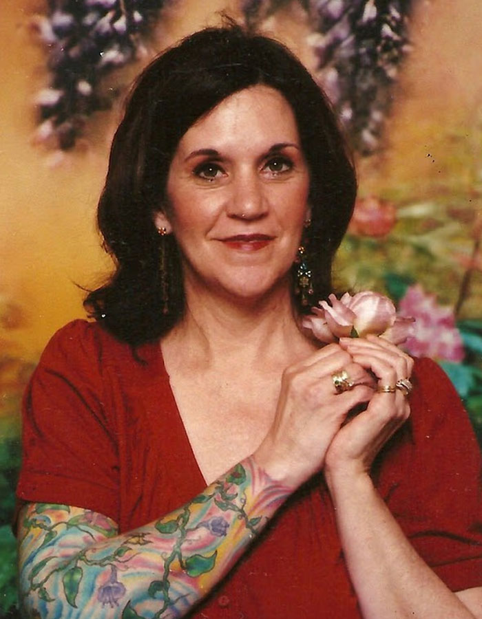 Woman with floral tattoo sleeve holding a pink flower, representing missing woman&rsquo;s body discovered in garage case.