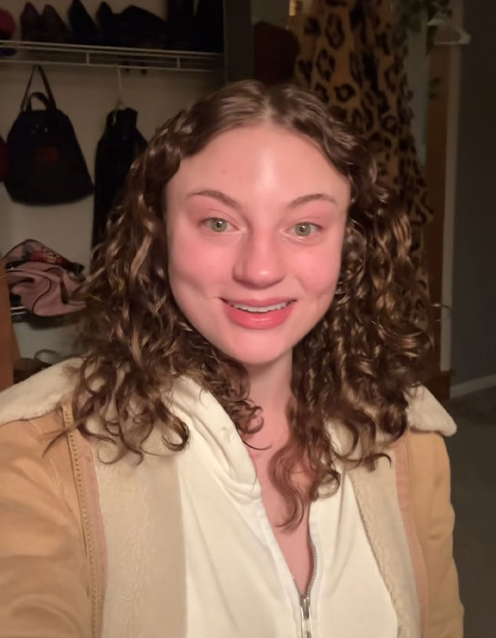 Young woman with curly hair smiling indoors, related to DoorDash driver arrested after recording undressed customer video. Young woman with curly hair smiling indoors, related to DoorDash driver arrested after recording undressed customer video.