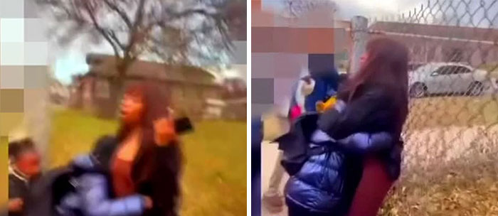 A pregnant woman being confronted outdoors by a group of young school kids wearing jackets near a chain-link fence.
