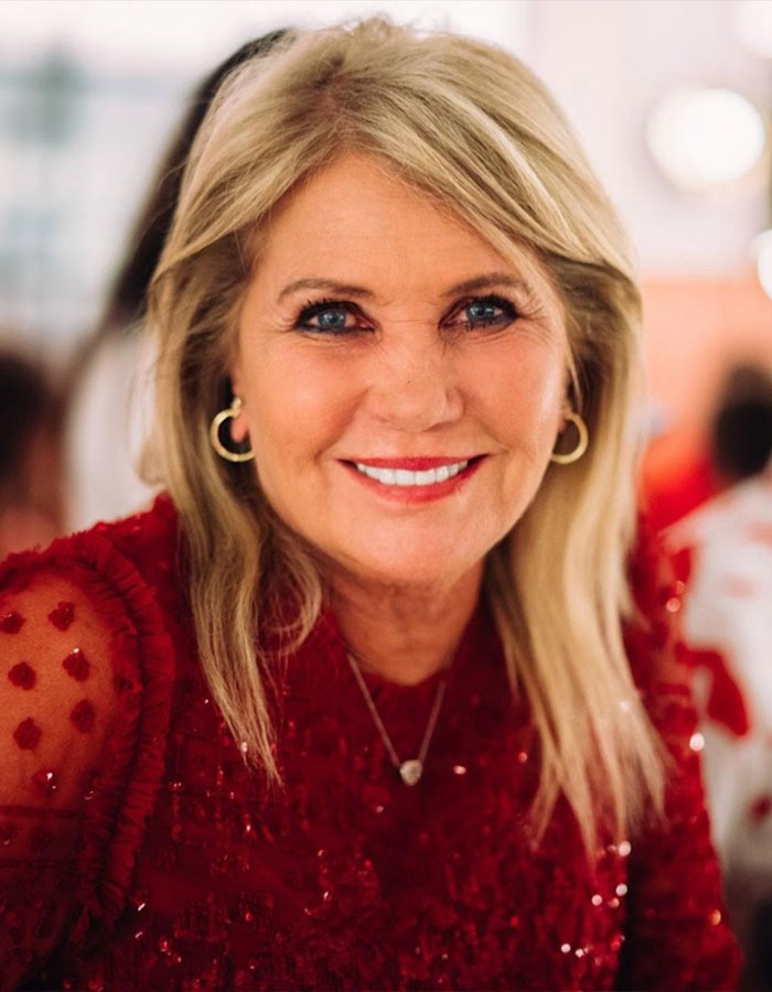 Close-up of a smiling woman in a red dress, related to Richard Branson's heartbreaking statement about his wife Joan.