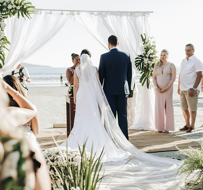 Bride and groom at beach wedding ceremony with guests standing nearby during spiritual bride event before wedding chaos.