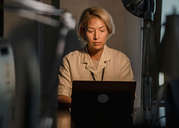 Person focused on laptop in dimly lit room, representing terrifying things found online experiences shared.