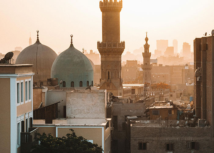 Cityscape at sunset with historic domes and minarets, illustrating one of the worst cities worldwide you should never visit.