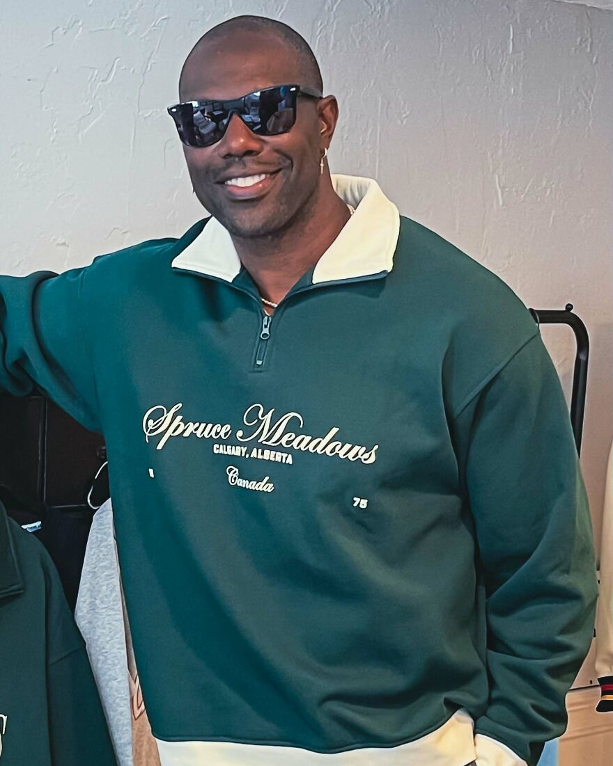 Smiling Terrell Owens in sunglasses and green Spruce Meadows sweatshirt featured on members-only fan pages.