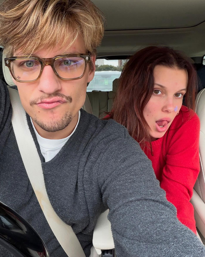 Young woman and man in a car, with Millie Bobby Brown breaking silence about adopting a baby at 21 after criticism. Young woman and man in a car, with Millie Bobby Brown breaking silence about adopting a baby at 21 after criticism.