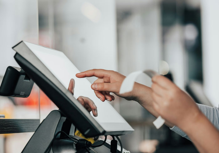 Person interacting with a touchscreen device while holding a receipt, illustrating instant karma moments concept.