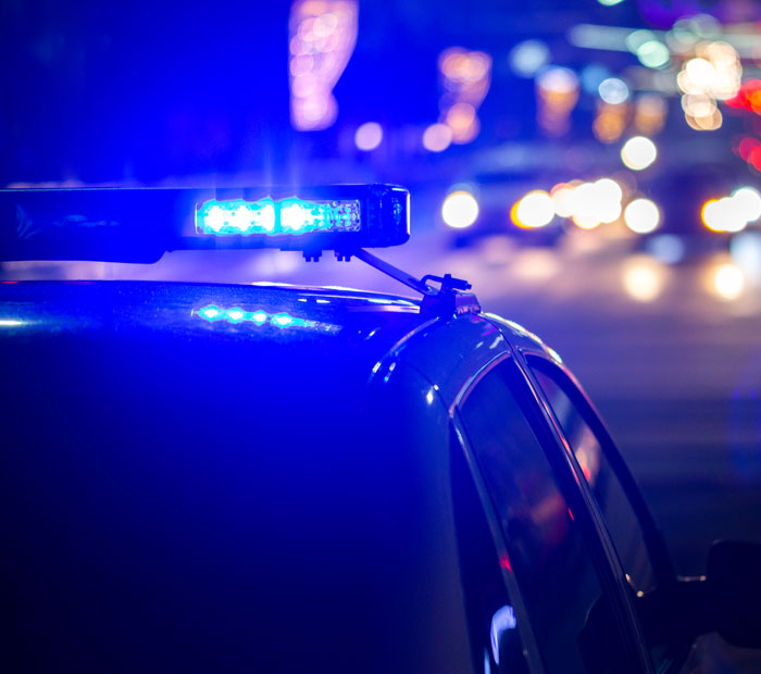 Police car with flashing blue lights at night, symbolizing lies people couldn’t believe they got away with.