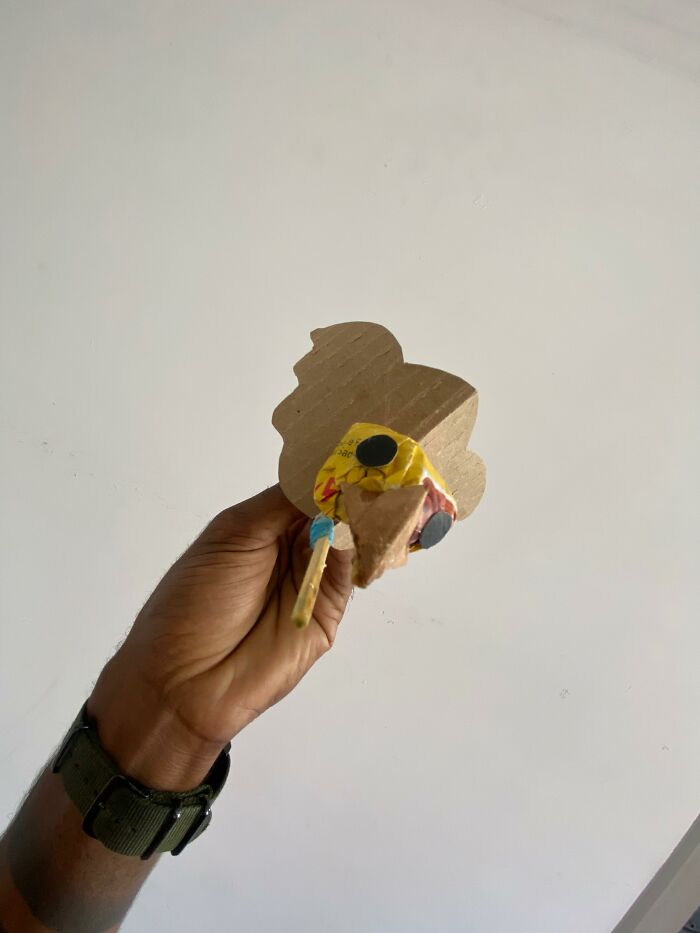 Hand holding a handmade cardboard mini bird used as a bird mom for rescuing a great kiskadee.