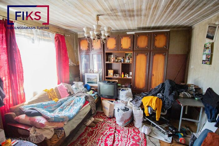 Cluttered and messy living room in a wild real estate listing filled with furniture, bags, and personal items.