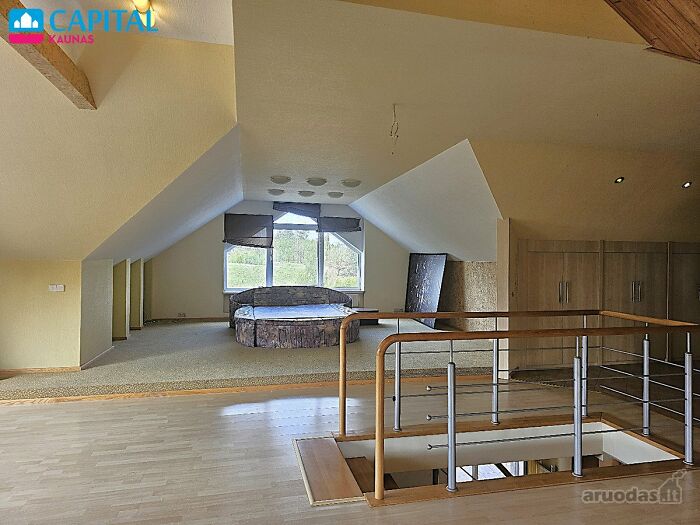 Spacious attic bedroom with sloped ceilings and rustic bed in wild real estate listing for property sale.