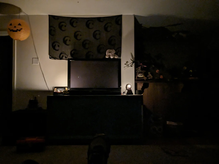 Dimly lit room with a blank TV screen and Halloween decorations, setting a spooky atmosphere for scary games with friends.