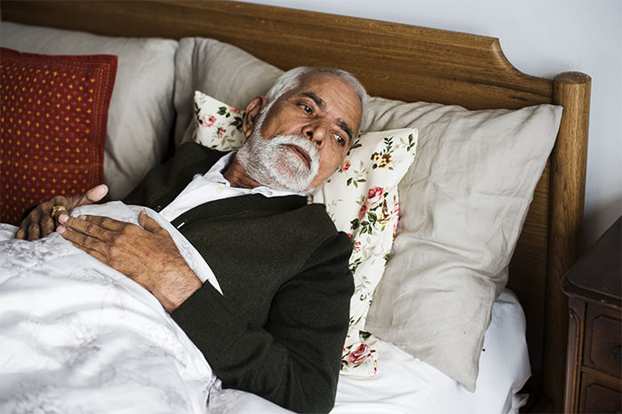 Elderly man lying in bed looking thoughtful, illustrating eerie patient stories that still haunt doctors today.