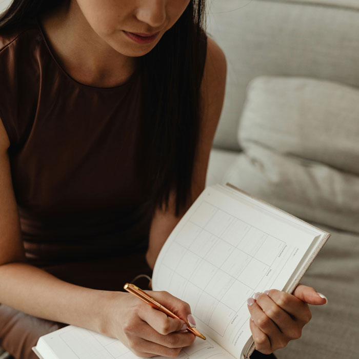 Woman focused on planning and writing in a notebook, illustrating change in how she treats her husband with chaos ensuing.