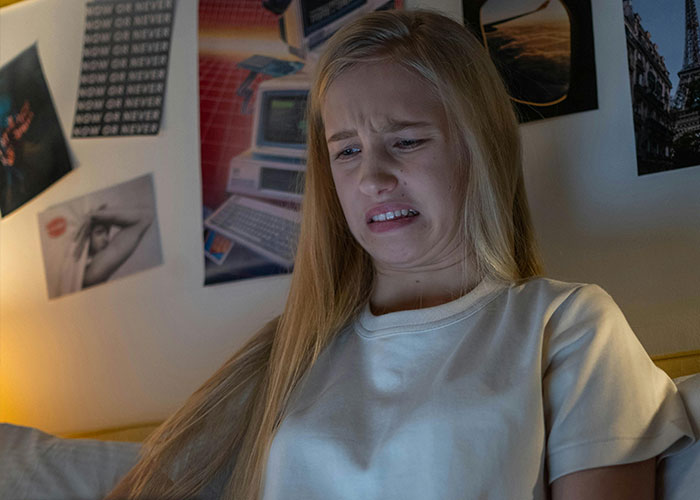 Young woman in bed reacting with disgust while browsing the most terrifying things found online on her laptop.